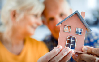 A senior couple holding a tiny model of a house