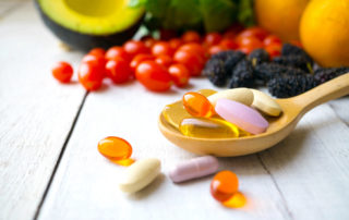 Vitamins and minerals laid out on a table with a wooden spoon