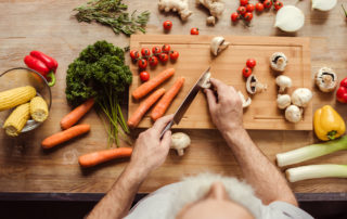 A senior man chops of veggies on a cutting board