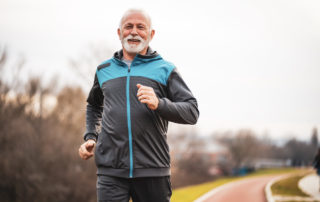 A senior man jogging outdoors in a park