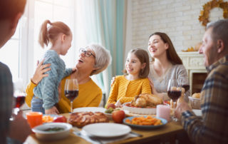 A senior woman and her family enjoy Thanksgiving together eating at a table