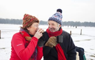 Couple outside of their independent living communities near Royal Oak, MI in winter enjoying a hot drink